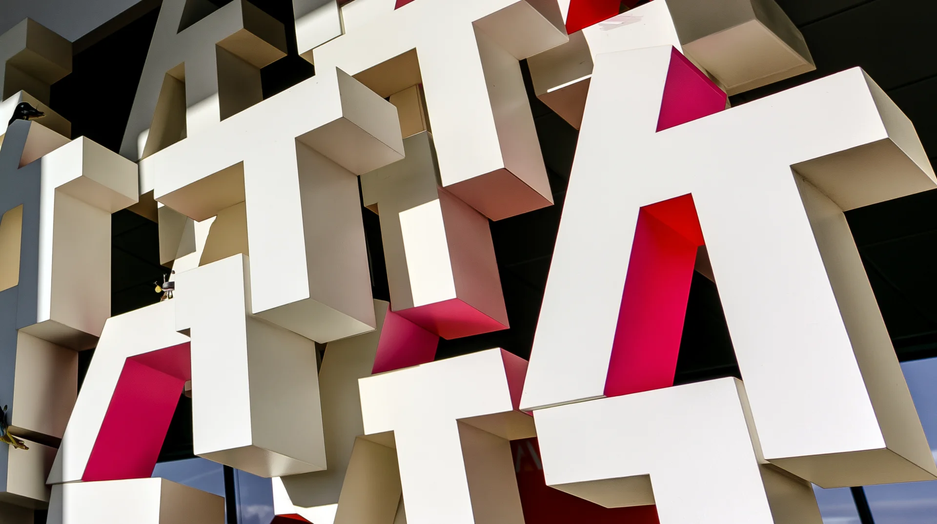 Bold three-dimensional signage typography in white and magenta